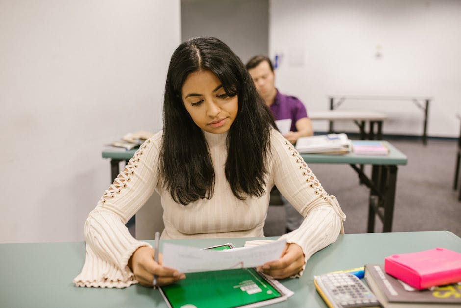 Student reviewing scholarship eligibility requirements on a laptop and printed forms