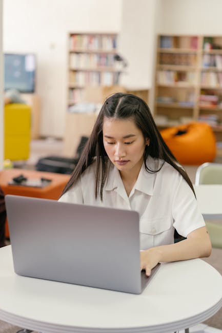 Student working at a laptop with notes, representing online/hybrid learning structure