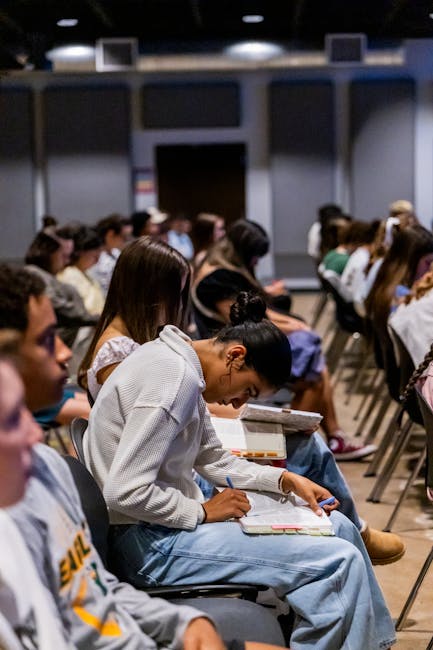 Student reviewing and summarizing lecture notes at a desk with a notebook