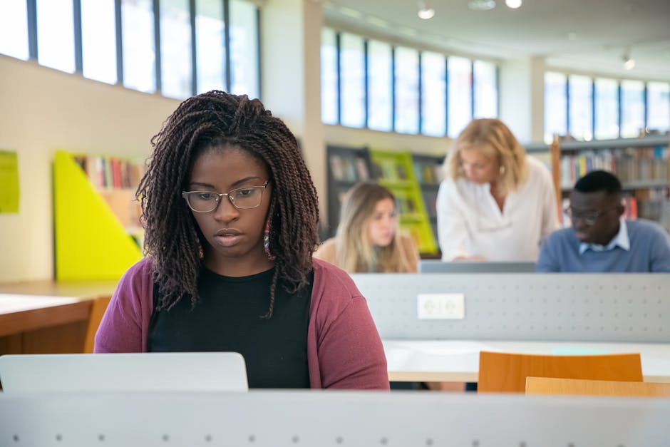Student searching academic papers on a laptop, surrounded by notes and books