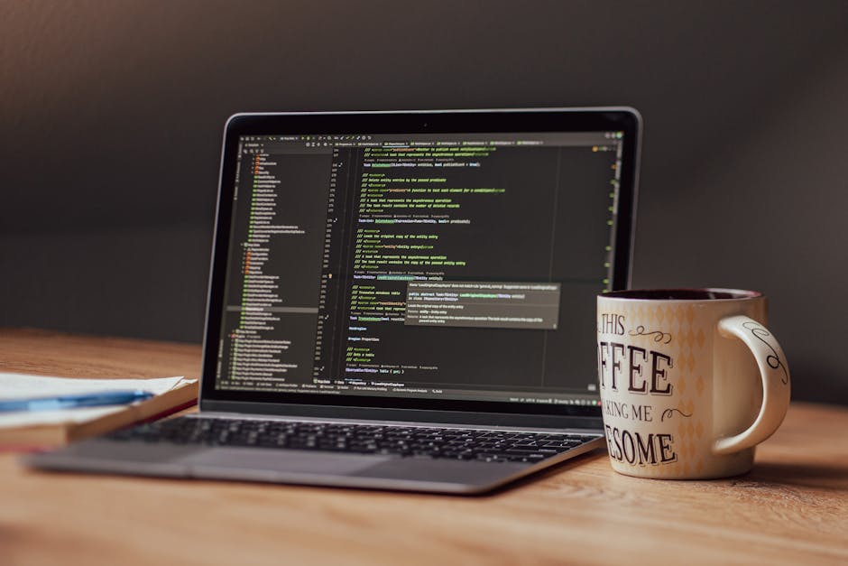 Student coding on a laptop with multiple screens for computer science coursework