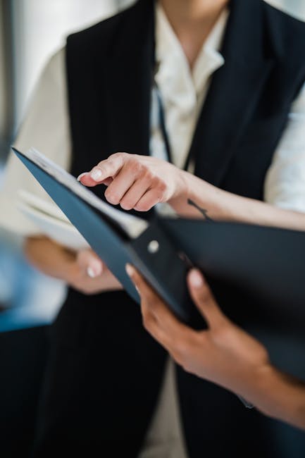 Two people in an office comparing application documents and notes at a desk