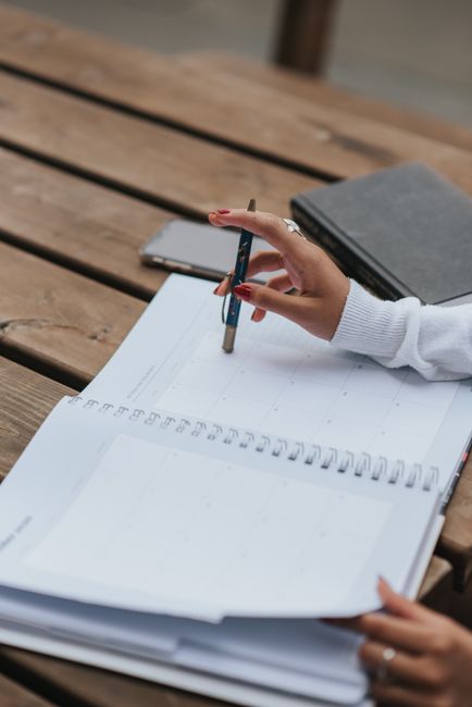 Student planning a weekly study schedule at a desk with books and timer