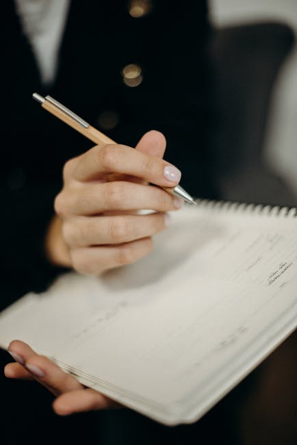 Student writing a campus tour scorecard on a notebook