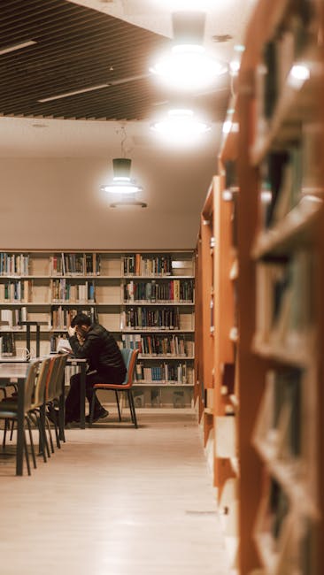 Students studying in a quiet library with desks, chairs, and power outlets