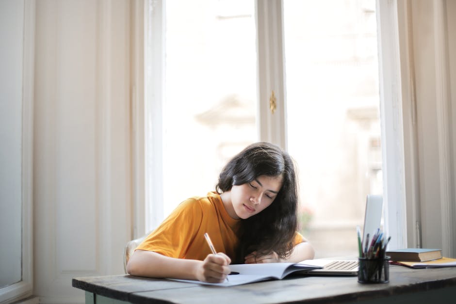 Student writing a personal statement at a desk with notes and laptop