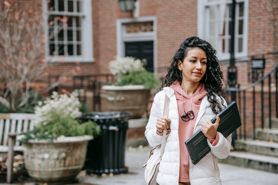 Person at a desk comparing university options with notes, laptop, and phone
